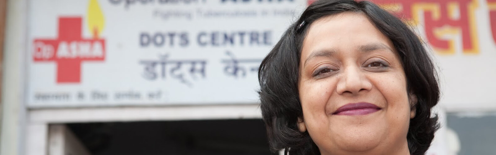a woman smiling with a medical sign at the background